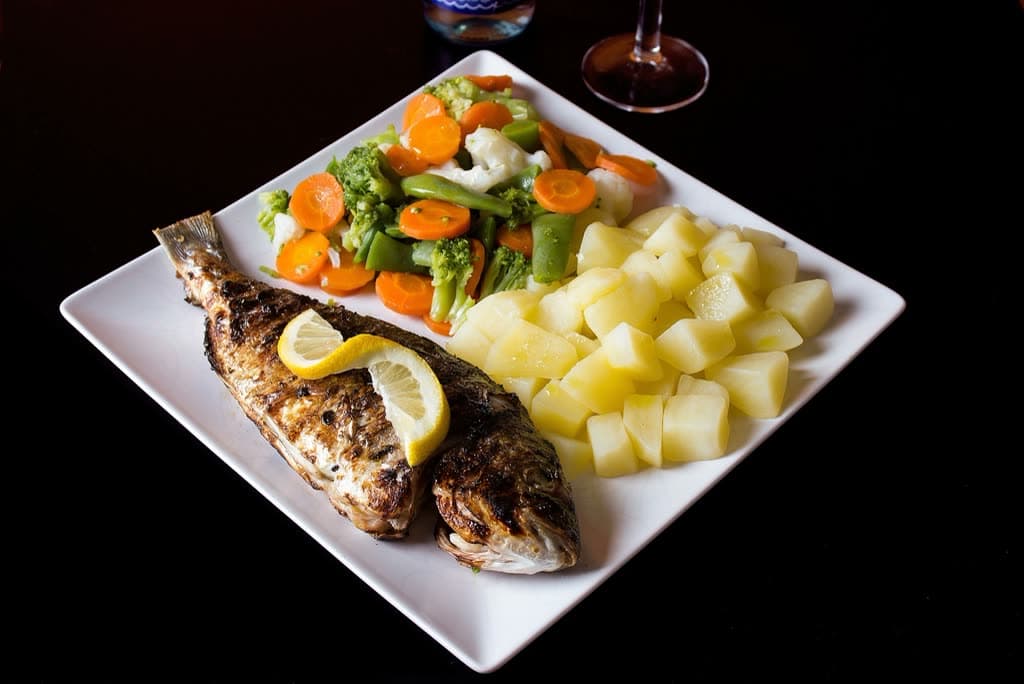 Beyaz tabakta fırında levrek, sebze ve patates